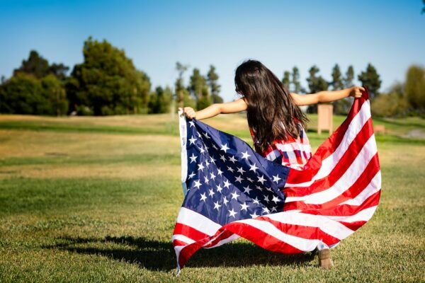 American Independence and the Seeds of Big Government girl holding US flag on grassland
